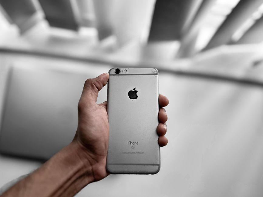 Mains ouvrant un carton contenant un smartphone reconditionné avec ses accessoires