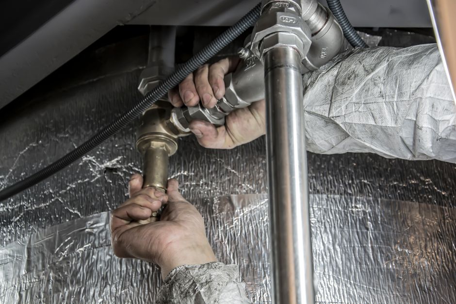 pompe de relevage installée dans un sous-sol, tuyaux et boîtier électrique visibles