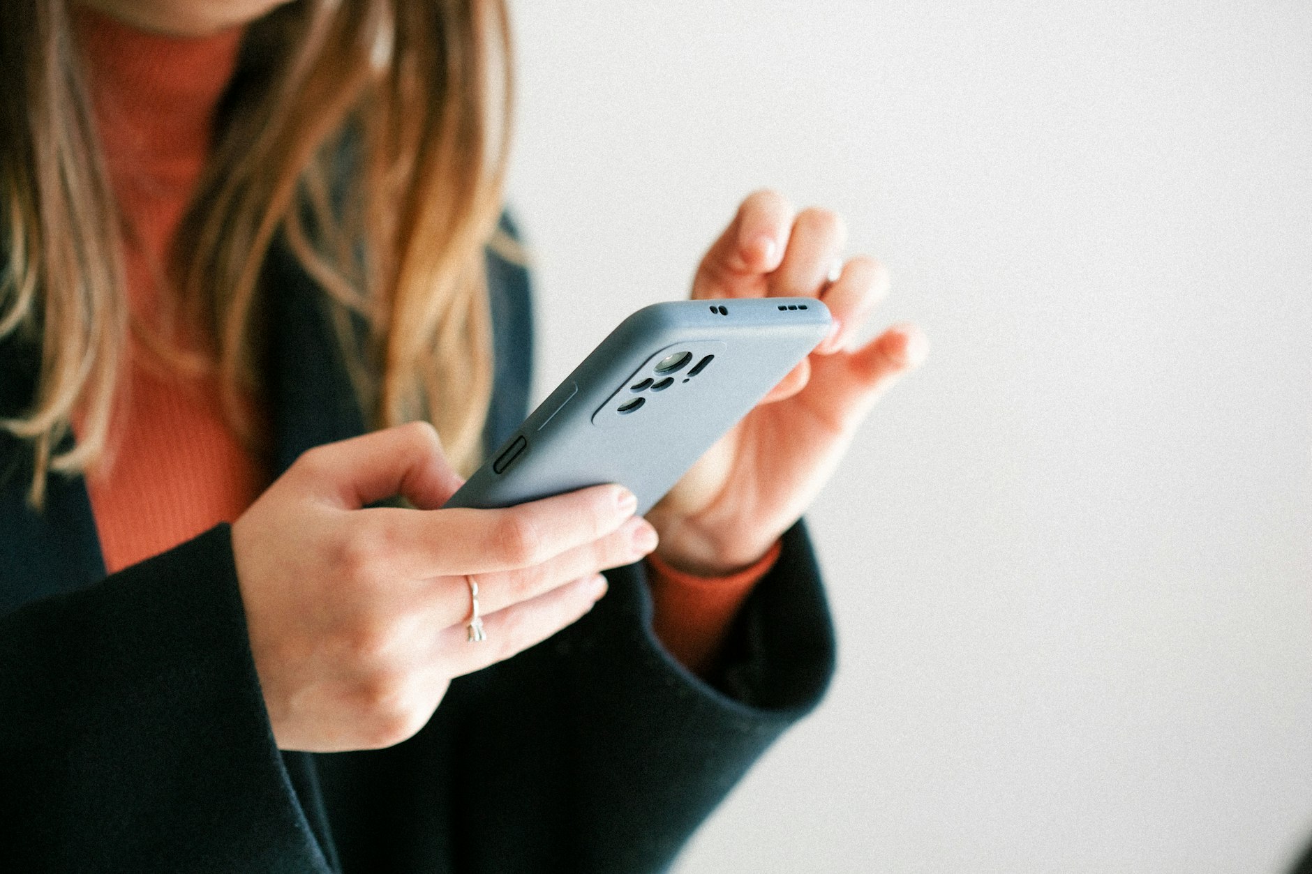 prise en main d'un smartphone récent par une personne en tenue professionnelle, plan serré sur les mains