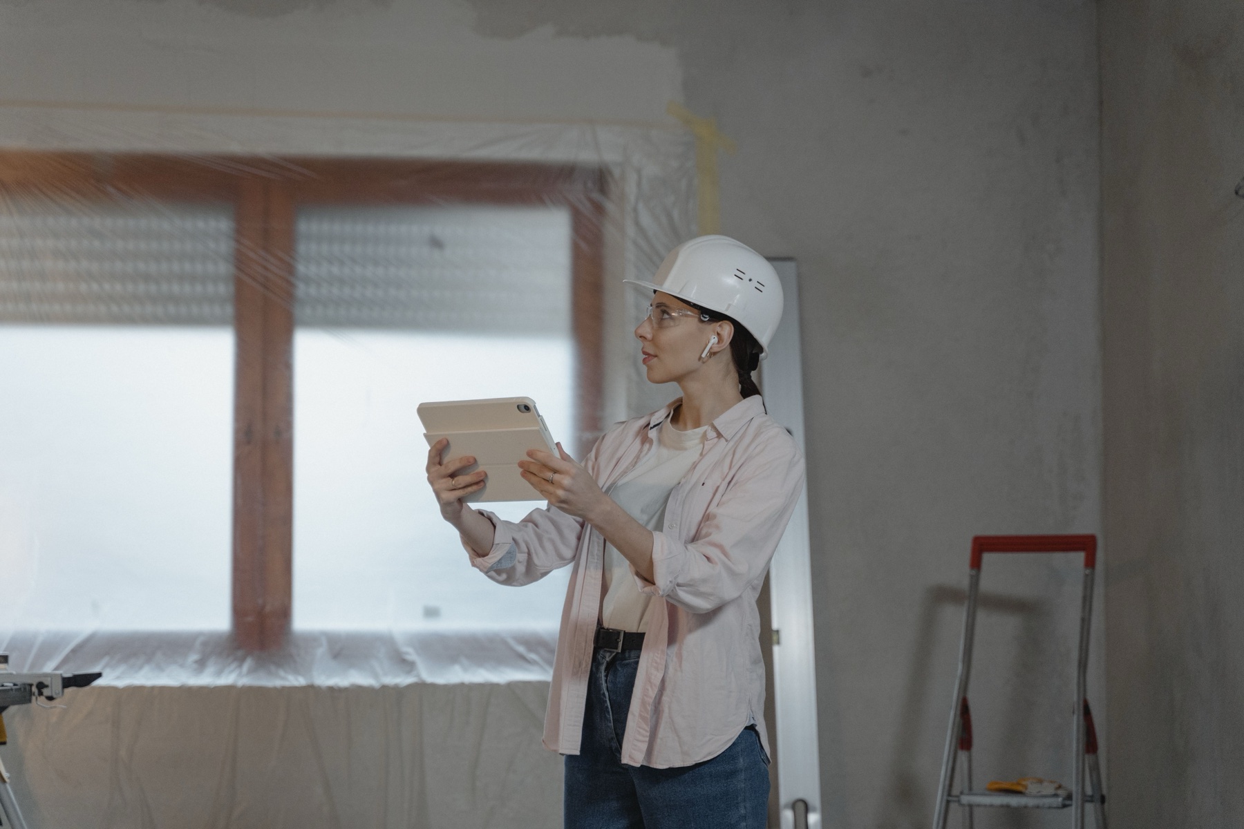 architecte en casque de chantier utilisant une tablette pour un relevé sur un site de construction