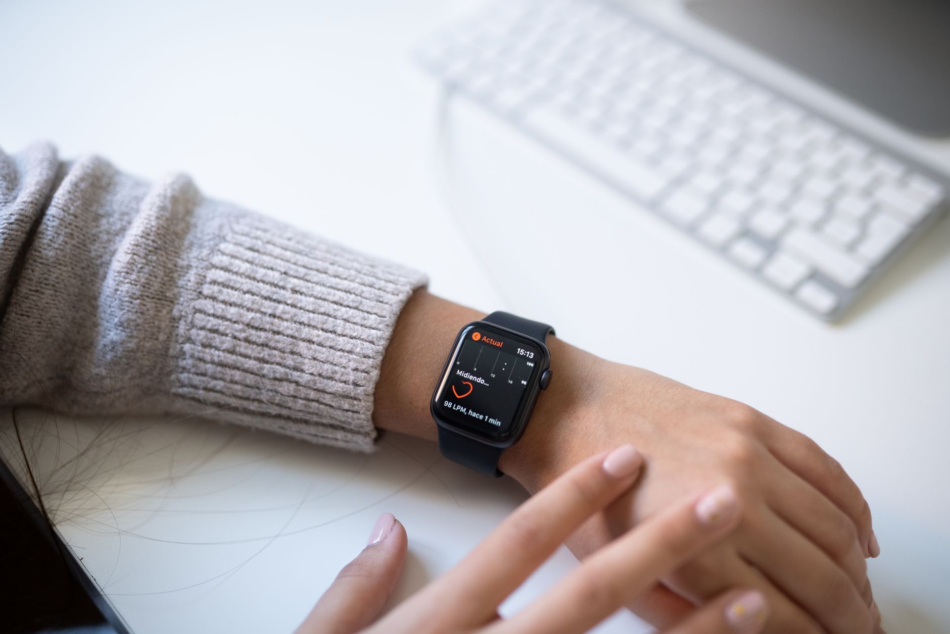 montre connectée au poignet affichant la fréquence cardiaque, posée près d'un clavier d'ordinateur
