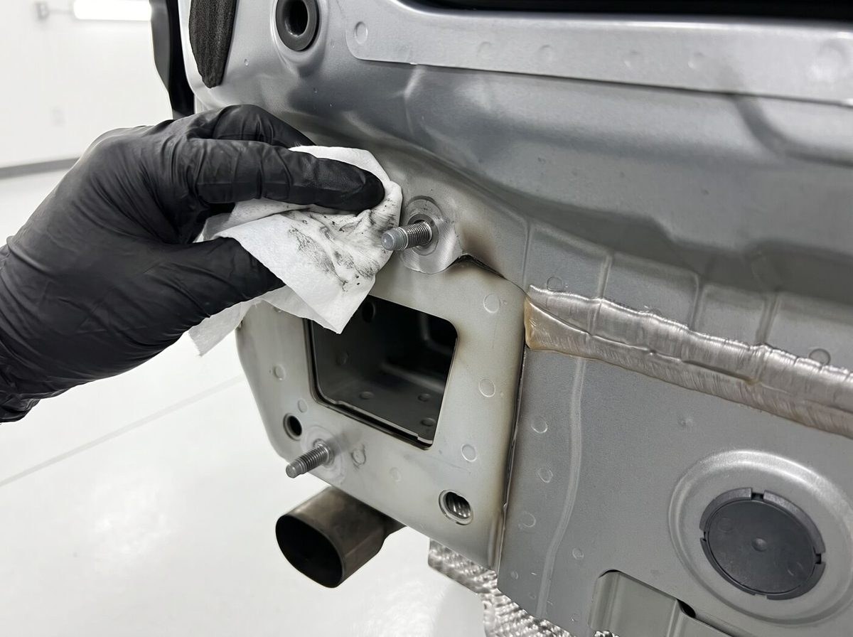 Technicien essuyant le point d'ancrage d'un attelage sur le châssis d'une voiture