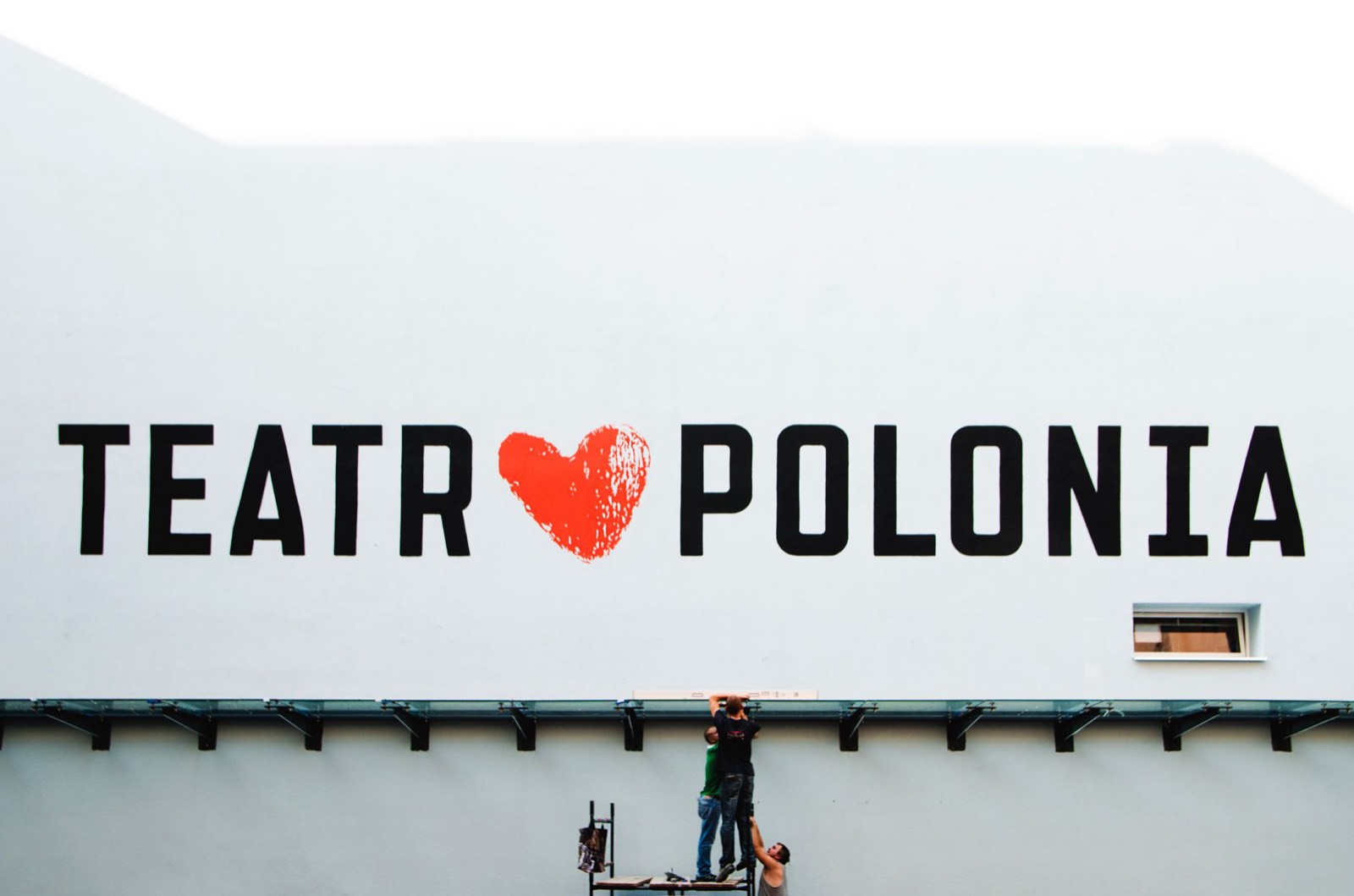 Technicien installant une enseigne publicitaire en PVC sur une façade de commerce