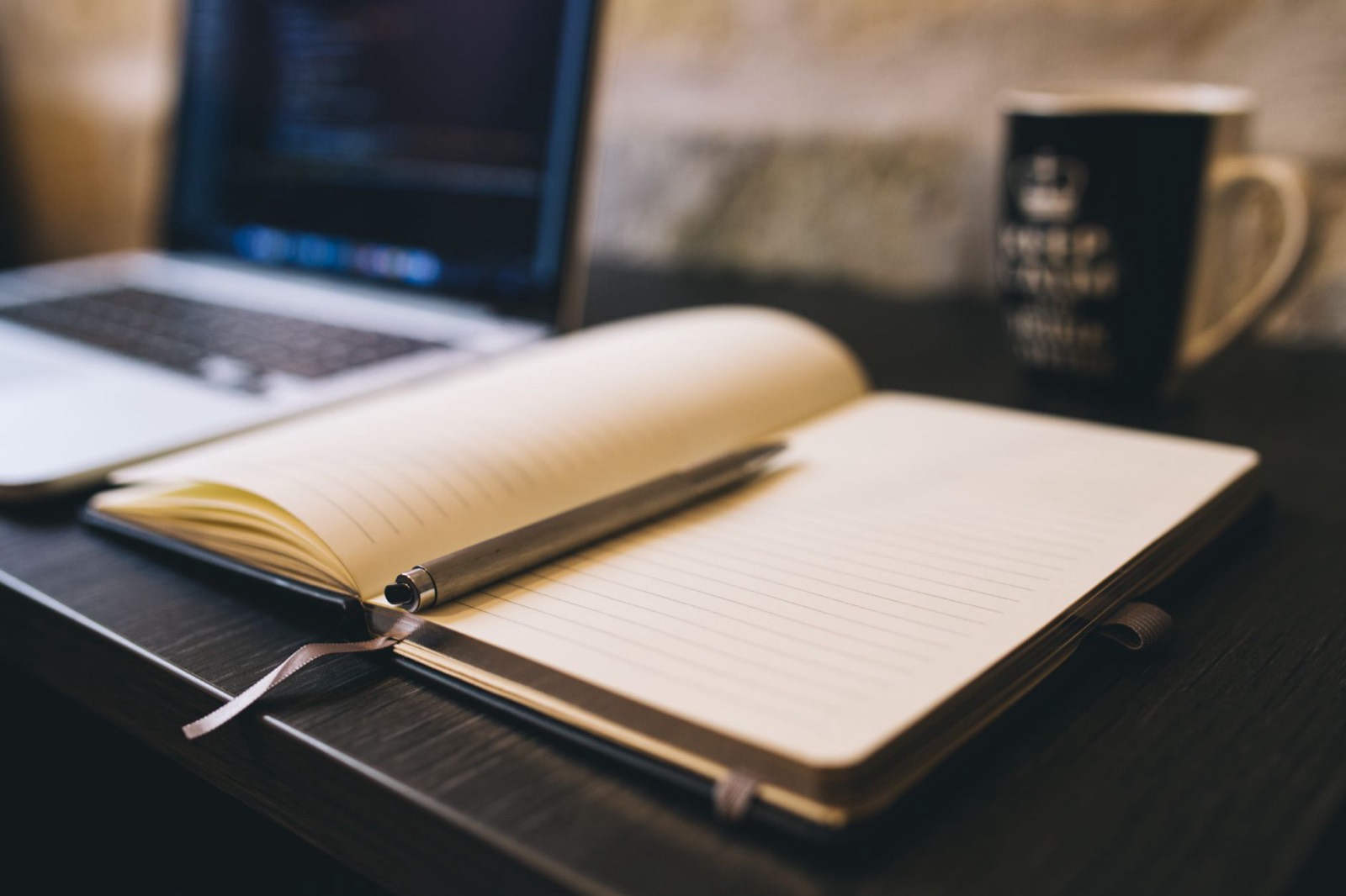 Carnet ouvert, stylo et tasse de café sur le bureau d'un concepteur-rédacteur