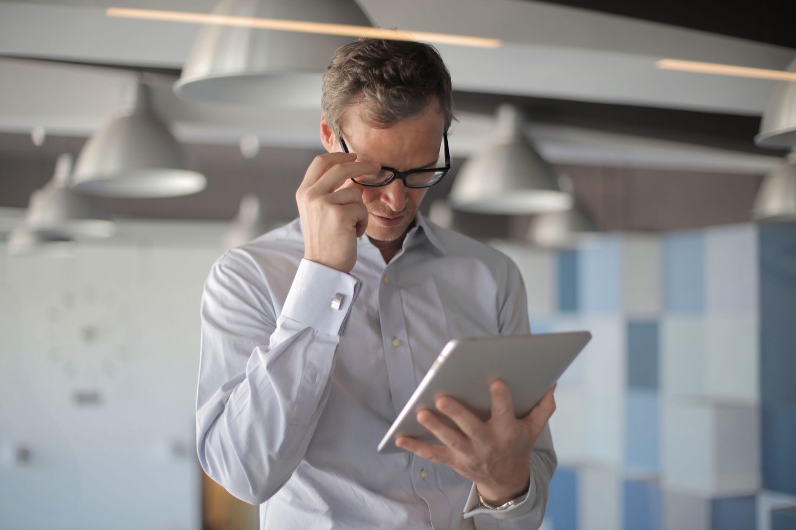 Collaborateur comparant les caractéristiques de plusieurs smartphones professionnels sur tablette